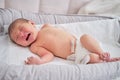 A newborn baby in a diaper is crying on the bed. Child is a boy in a cocoon on a cot Royalty Free Stock Photo