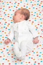 Newborn baby dressed in white sleeping on her back