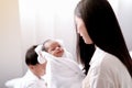 Newborn baby express question and curious emotion during her mother holding and her older brother play around in the background
