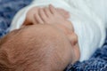 Newborn - baby, face close-up. The sleeping Newborn boy under a white knitted blanket lies on the blue fur. Royalty Free Stock Photo