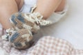 Newborn baby feet close up in wool brown knitted socks booties on a white blanket. The baby is in the crib Royalty Free Stock Photo