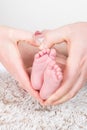 Newborn baby feet in heart hands fingers of mother father birth and family symbol Royalty Free Stock Photo