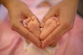 Newborn baby feet in its mother`s hands shaped like a heart. Mother showing her love and affection Royalty Free Stock Photo