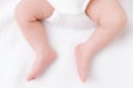 Newborn baby feet and legs on white bed background Royalty Free Stock Photo