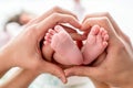 Newborn baby feet on mom and dad hands, shape like a lovely heart. happy family concept