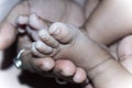 Newborn Baby Feet in Mother Hands. Beautiful infant little baby fingers and foot in mother`s palm. Close-up. Child health care an Royalty Free Stock Photo