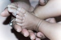 Newborn Baby Feet in Mother Hands. Beautiful infant little baby fingers and foot in mother`s palm. Close-up. Child health care an Royalty Free Stock Photo