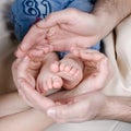 Newborn baby feet parents holding in hands.Mom and Dad hold baby legs. Royalty Free Stock Photo