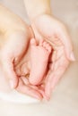 Newborn baby foot parent holding in hands. Close up. Royalty Free Stock Photo