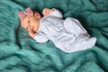 Newborn baby girl with bow in white footed pajamas.