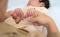 Newborn baby girl or boy holding mother hands. Mom and child on white bed Royalty Free Stock Photo