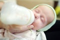 Newborn baby girl in her mother arms. Mom feeding offspring milk from bottle. Artificial nutrition for babies Royalty Free Stock Photo