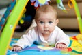 Newborn baby girl lying on tummy on carpet with toys Royalty Free Stock Photo