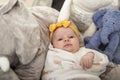 Newborn baby girl posing with a twinkle in her eyes and wearing a yellow bandanna with yellow bow.. Royalty Free Stock Photo