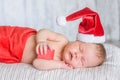 Newborn baby girl in red santa hat sleeping with a gift in hands Royalty Free Stock Photo