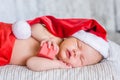 Newborn baby girl in red santa hat sleeping with a gift in hands Royalty Free Stock Photo