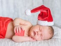 Newborn baby girl in red santa hat sleeping with a gift in hands Royalty Free Stock Photo