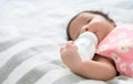 Newborn baby girl sleeping alone on bed and drinking milk from bottle Royalty Free Stock Photo