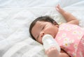 Newborn baby girl sleeping alone on bed and drinking milk from bottle Royalty Free Stock Photo