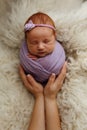 Newborn baby girl is sleeping in a cocoon pose potato bag in his mother`s arms. The concept of safety and happiness Royalty Free Stock Photo