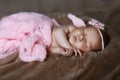 Newborn baby girl sleeping cute, covered with soft pink scarf, neatly folded under a pen with a small head with a pink bow, set Royalty Free Stock Photo