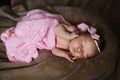 Newborn baby girl sleeping cute, covered with soft pink scarf, neatly folded under a pen with a small head with a pink bow, set Royalty Free Stock Photo