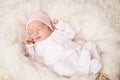 Newborn Baby Girl sleeping over Fluffy White Blanket. Adorable One Month Child in Pink Bodysuit dreaming over Beige Furry Carpet Royalty Free Stock Photo