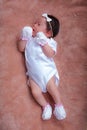 Newborn baby girl, sleeping on soft cushion and wearing a tiny bow Royalty Free Stock Photo