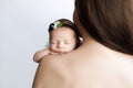 A newborn baby girl sleeps on her mother`s bare shoulder with her hand pressed to her cheek