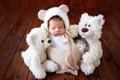 Newborn baby girl two weeks sweetly sleeping among soft toys bears in a hat with ears on a wooden background Royalty Free Stock Photo