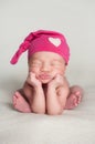 Newborn Baby Girl Wearing a Pink Top Knot Cap