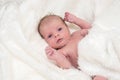 Newborn baby girl on white fluffy coverlet