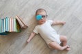 Newborn baby in glasses with books. A little boy in white clothes and blue . Beautiful portrait of a toddler. Big-eyed baby. Remot