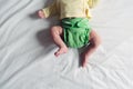 Newborn baby in green reusable diaper on a white sheet. Modern eco friendly cloth nappy for infant child hygiene. Sustainable