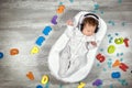 Newborn baby in headphones sleeps in a special mattress Baby cocoon, on a wooden floor multicolored letters around. Calm Royalty Free Stock Photo