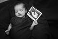 newborn baby holding ultrasound copy in hand and sleeping at mother palm in black and white Royalty Free Stock Photo