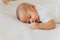 Newborn baby kid sleeping on his tummy on bed at home. Asian child bottom up sleeping position Royalty Free Stock Photo