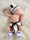 Newborn baby in a knitted suit yawns while lying on a fur blanket. Beautiful portrait of a small child, two weeks ago Royalty Free Stock Photo