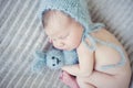 Newborn baby with knitted toy and cap sleeping on blanket Royalty Free Stock Photo