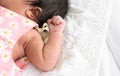 Newborn adorable baby girl or boy with fingers in fist sleeping on white bed at home. Copy space Royalty Free Stock Photo