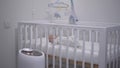 A newborn baby lies in a crib against the background of an ultrasonic humidifier. Royalty Free Stock Photo