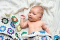 Newborn baby lying on bed, covered by a crocheted blanket. Top view. Royalty Free Stock Photo