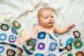 Newborn baby lying on bed, covered by a crocheted blanket. Top view. Royalty Free Stock Photo