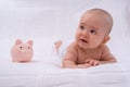 Newborn baby lying on the crib and a pink piggy bank nearby. Savings and savings concept Royalty Free Stock Photo