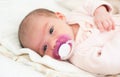 Newborn baby is lying on its side with white soother in mouth Royalty Free Stock Photo