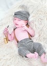 a newborn baby is lying on a white fur in a cap and with a guitar Royalty Free Stock Photo