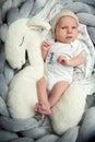 Newborn Baby Portrait looking at camera lying down on White Plush Toy Horse. One month little Child in White Bodysuit. Infant Royalty Free Stock Photo