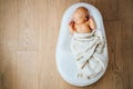 Newborn baby quietly sleeps in a special orthopedic mattress Baby cocoon, on a wooden floor. Calm and healthy sleep in newborns