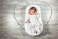 Newborn baby sleeps in a special orthopedic mattress Baby cocoon, on a wooden floor and heart from garlands. Calm and Royalty Free Stock Photo