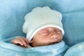 Newborn Baby Red Cute Face Portrait Early Days Sleeping In Medical Glass Bed On Blue Background. Child At Start Minutes Royalty Free Stock Photo